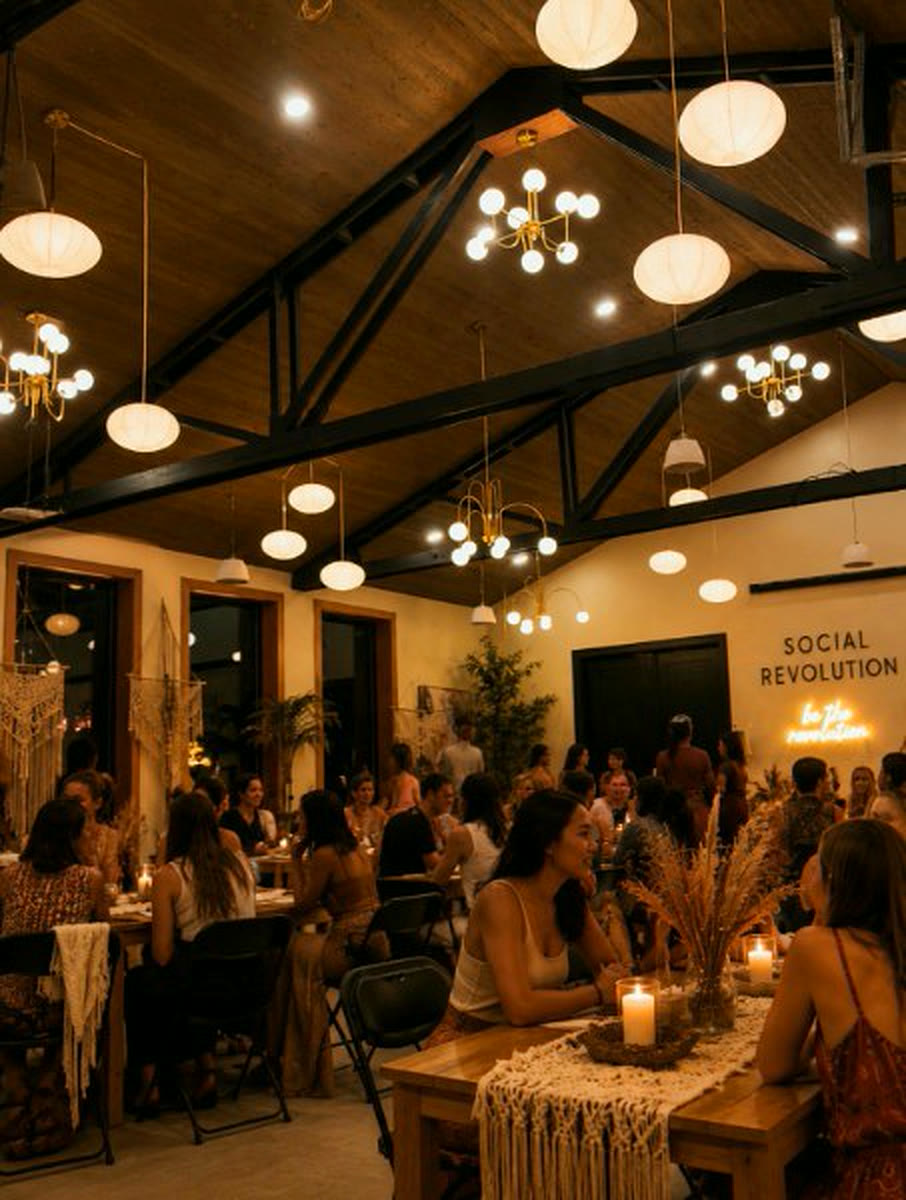 The hall full of guests at night under the globe pendants, the Social Revolution sign lit behind them