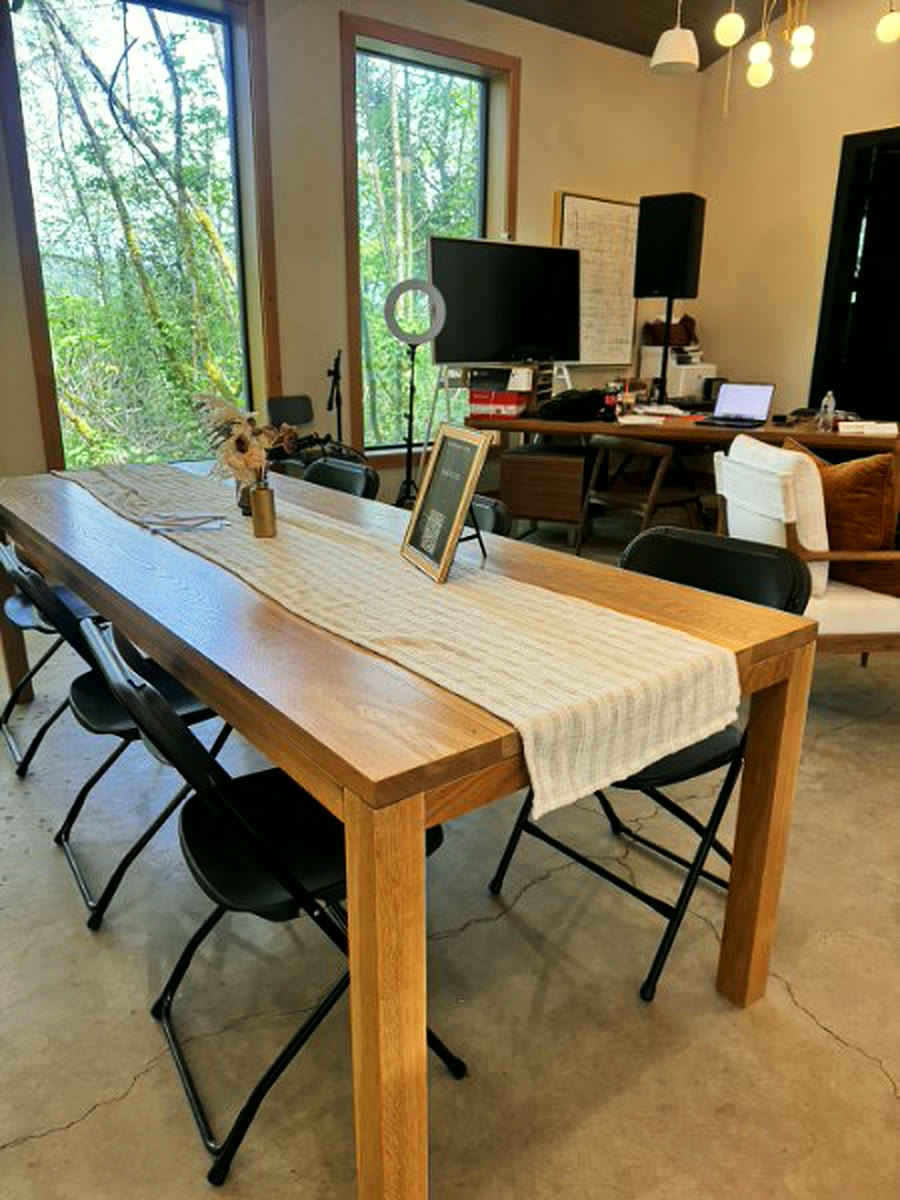 A long meeting table set for a working session, the forest through the window behind it
