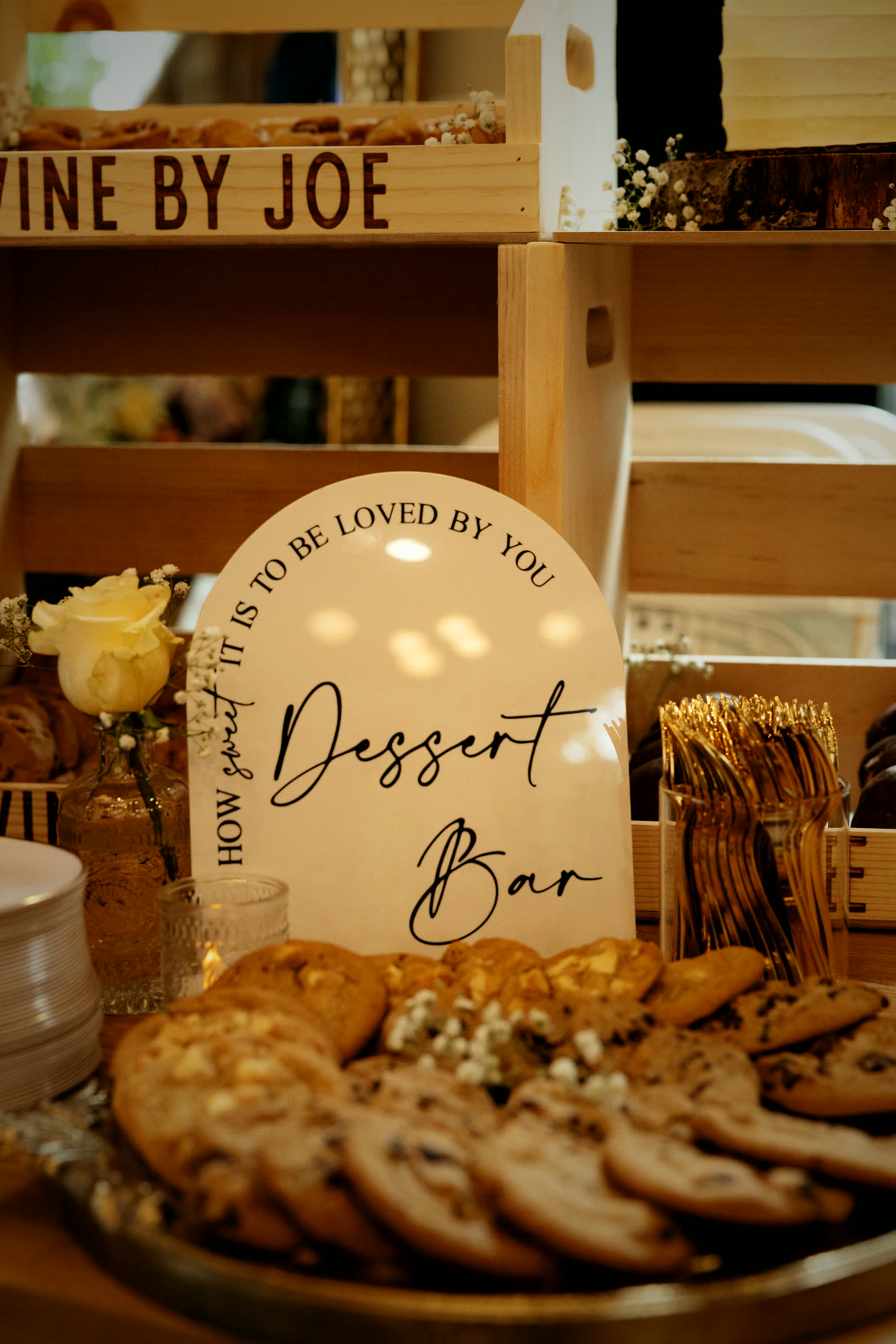 The dessert bar with an arched sign, gold flatware and baby's breath