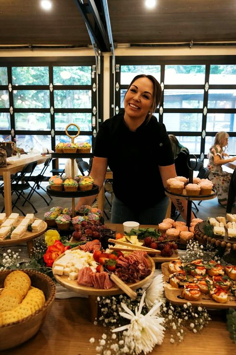 A caterer behind a grazing table of charcuterie and pastries at a baby shower