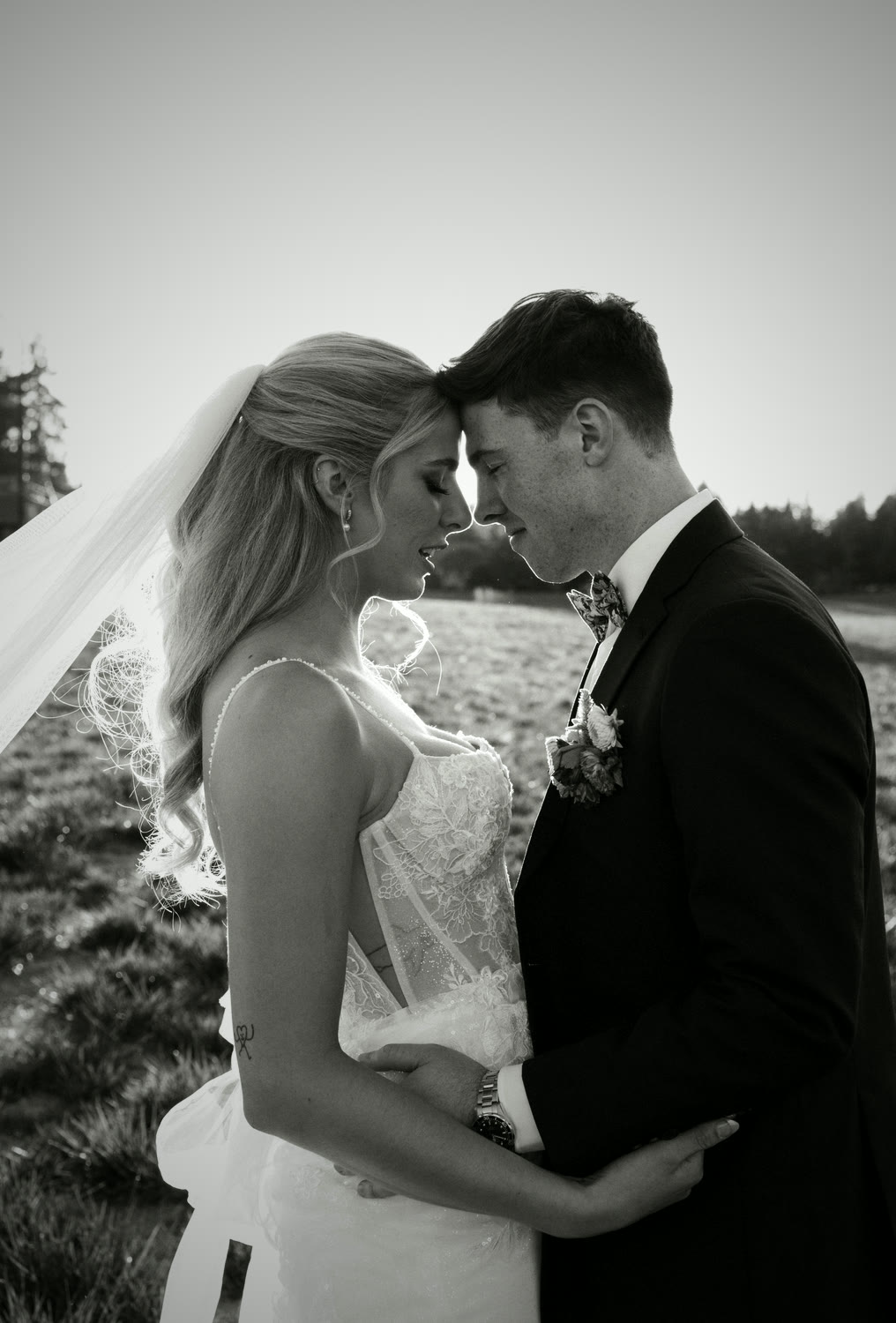 A couple forehead to forehead in the open meadow, in black and white