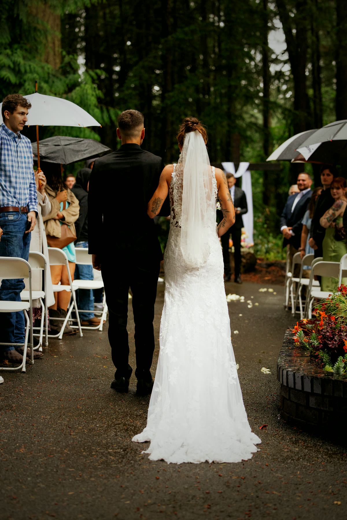 Guests holding umbrellas along the aisle during a rainy ceremony
