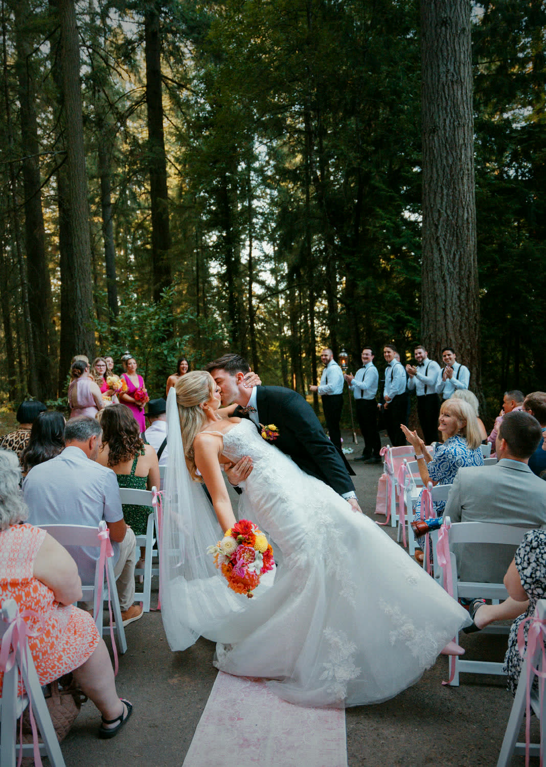 A couple kissing in the aisle on the way back out, guests applauding